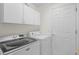 Bright laundry room with modern washer, dryer, and ample storage cabinets at 11250 Hollander Ave, Hudson, FL 34667