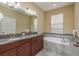 Bathroom featuring double vanity, soaking tub, granite countertops, and natural light at 11407 Acacia Grove Ln, Riverview, FL 33579