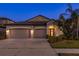 Charming exterior view of a single-story home with a three-car garage, showcasing its curb appeal at dusk at 11407 Acacia Grove Ln, Riverview, FL 33579
