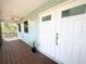 Inviting front porch with double doors, ceiling fan, and quaint sconce lighting at 16204 3Rd E St, Redington Beach, FL 33708