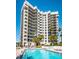 This condo exterior is situated beside palm trees, lounge chairs, and a pool at 1660 Gulf Blvd # Ph-7, Clearwater Beach, FL 33767