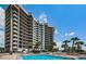 Exterior view of a building with a pool, patios, palm trees, and beach access at 1660 Gulf Blvd # Ph-7, Clearwater Beach, FL 33767