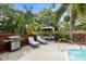 Relaxing pool patio featuring loungers, an outdoor kitchen, gazebo and beautiful landscaping at 1686 Spottswood Cir, Palm Harbor, FL 34683