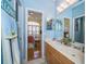 Bright bathroom with double vanity, blue walls, and a peek into a bedroom at 18002 Forest Retreat Ln, Tampa, FL 33647