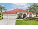 Charming single-story home with a red tile roof, lush landscaping, and a three-car garage at 18002 Forest Retreat Ln, Tampa, FL 33647