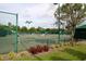 View of the community tennis court, surrounded by lush landscaping and a green fence at 18002 Forest Retreat Ln, Tampa, FL 33647