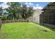 Well-maintained backyard with a green lawn, wooden fence, and access to a screened porch at 23253 Granite Pl, Land O Lakes, FL 34639
