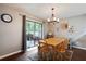 Bright dining area with a chandelier, wood-look floors, and sliding doors to the screened patio at 23253 Granite Pl, Land O Lakes, FL 34639