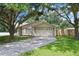 Charming single-story home with a well-manicured lawn, mature trees, and a spacious driveway leading to an attached two-car garage at 23253 Granite Pl, Land O Lakes, FL 34639