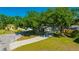Exterior of a home featuring mature trees, a long driveway, green lawn, and manicured landscaping at 23253 Granite Pl, Land O Lakes, FL 34639
