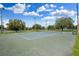Outdoor community tennis court with green and blue surface and lighting under a blue sky with fluffy clouds at 23253 Granite Pl, Land O Lakes, FL 34639