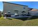 Exterior view of a backyard with patio featuring grill, table, sofa, and green lawn at 238 Argyll Dr, Spring Hill, FL 34609