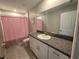 Well-lit bathroom featuring a granite countertop, a large mirror, and a shower with pink polka dot curtains at 238 Argyll Dr, Spring Hill, FL 34609