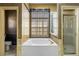 Bathroom featuring a sunken tub beneath a large window, tilework and glass shower at 28451 Great Bend Pl, Wesley Chapel, FL 33543