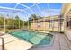 Screened-in pool with clear blue water, tiled patio and view of trees in the backyard at 28451 Great Bend Pl, Wesley Chapel, FL 33543