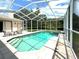 Screened-in pool with clear blue water, tiled patio and seating area with decorative table and chairs at 28451 Great Bend Pl, Wesley Chapel, FL 33543