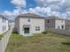 A spacious backyard with healthy green grass, surrounded by a white fence and a view of a two story home at 30739 Penny Surf Loop, Wesley Chapel, FL 33545