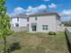 A spacious backyard with healthy green grass, surrounded by a white fence and a view of a two story home at 30739 Penny Surf Loop, Wesley Chapel, FL 33545