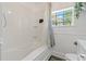 Bright bathroom featuring a tiled shower-tub, white vanity and a window providing natural light at 3113 W Sligh Ave, Tampa, FL 33614