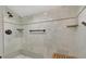 Walk-in shower with stone-look tile walls, rainfall shower head, and convenient shelving for toiletries at 3113 W Sligh Ave, Tampa, FL 33614