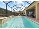 Beautiful pool with waterfall feature surrounded by a screened-in lanai and lush landscaping at 31382 Chesapeake Bay Dr, Wesley Chapel, FL 33543