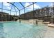 Backyard screened-in pool with a beautiful waterfall feature and lush landscaping at 31382 Chesapeake Bay Dr, Wesley Chapel, FL 33543