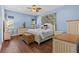 Charming bedroom with blue walls, hardwood floors, a ceiling fan, and natural light from a large window at 314 Crosswinds Dr, Palm Harbor, FL 34683