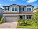 Beautiful two-story home showcasing a manicured lawn, paver driveway, and a welcoming gray exterior at 33263 Sycamore Leaf Dr, Wesley Chapel, FL 33545