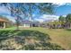 Expansive backyard with a lush lawn, mature trees, and a covered patio area at 34516 Heavenly Ln, Dade City, FL 33525