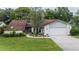 A single-Gathering home featuring a well-manicured lawn, mature landscaping, and a two-car garage at 34527 Cedarfield Dr, Dade City, FL 33523