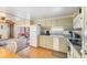 Functional kitchen featuring white appliances, light green cabinets, and an adjacent dining area at 37025 Lois Ave, Zephyrhills, FL 33542