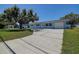 Exterior of light blue home with a long driveway, green grass, and large shade tree at 3841 Wahoo Se Dr, St Petersburg, FL 33705