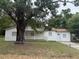 A single-story house with a white exterior, a porch, and a large tree in the yard at 3918 E Clifton St, Tampa, FL 33610