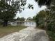 A single-story home featuring a white exterior, a porch, and a cracked concrete driveway at 3918 E Clifton St, Tampa, FL 33610