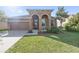 Charming stucco home featuring a two-car garage, arched entryway, and well-manicured lawn at 5108 Suncatcher Dr, Wesley Chapel, FL 33545