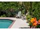 Tranquil pool area featuring comfortable rocking chairs amidst vibrant tropical foliage and blooming flowers at 6113 Kipps Colony W Dr, Gulfport, FL 33707