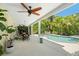 Covered patio featuring a fan, outdoor dining table and seating overlooking a pool with garden views at 6113 Kipps Colony W Dr, Gulfport, FL 33707