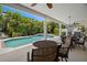 An inviting covered patio with an outdoor dining set overlooks a sparkling pool and tropical landscaping at 6113 Kipps Colony W Dr, Gulfport, FL 33707