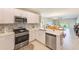 Open-concept kitchen with stainless steel appliances, white cabinetry, and a view of the adjacent dining and living spaces at 6333 Milestone Loop, Palmetto, FL 34221