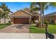 Charming home featuring a two-car garage, stone accents, a brick driveway and lush landscaping at 11656 Lake Blvd, New Port Richey, FL 34655