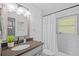 Bathroom with a white tiled shower, vanity with dark countertop and a plant at 1414 Sunset Ln, Lutz, FL 33549