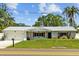 Charming single-story home with a well-manicured lawn, a metal roof, and beautiful landscaping at 1414 Sunset Ln, Lutz, FL 33549