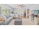 Spacious living room with modern decor, featuring an elegant gray sectional, hardwood flooring, and a ceiling fan at 1414 Sunset Ln, Lutz, FL 33549