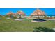 Three grass hut umbrellas sit on a manicured lawn next to the beach at 1460 Gulf Blvd # 1206, Clearwater Beach, FL 33767