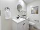 Bright bathroom boasts a white vanity, round mirror, decorative art, and modern black fixtures at 1469 S Hillcrest Ave, Clearwater, FL 33756