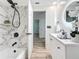 Well-lit bathroom with marble-look tile shower, white vanity, and wood-look flooring at 1469 S Hillcrest Ave, Clearwater, FL 33756