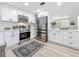 Charming kitchen featuring stainless steel appliances, white cabinetry, and wood-look flooring at 1469 S Hillcrest Ave, Clearwater, FL 33756