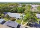 Aerial view showcases a flat-roofed home with lush greenery, mature landscaping, and a shared carport area at 1535 Nursery Rd # 111, Clearwater, FL 33756