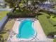 Aerial view showcases a kidney-shaped pool with surrounding patio, lush green hedges, and outdoor seating at 1535 Nursery Rd # 111, Clearwater, FL 33756