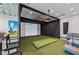 Indoor golf simulator room features a projector screen, putting green, and comfortable seating at 16709 Barnwood Pl, Bradenton, FL 34211